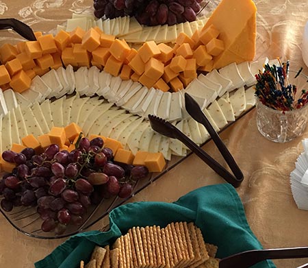 a tray of assorted cheeses with tongs and crackers